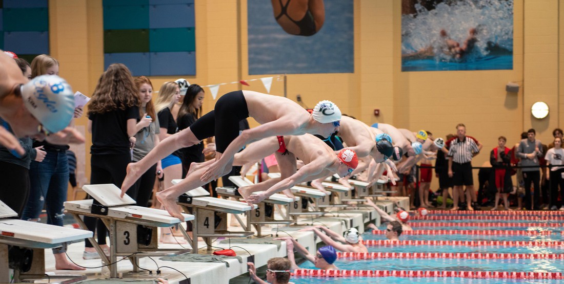 Swimmers on the starting blocks during a swim meet.